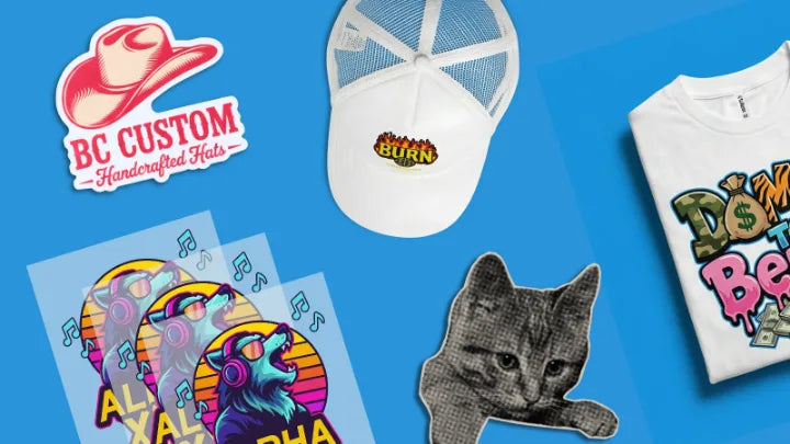 Custom products laid out on blue: a die-cut sticker, a printed trucker hat, DTF transfers, a cat sticker and a printed t-shirt