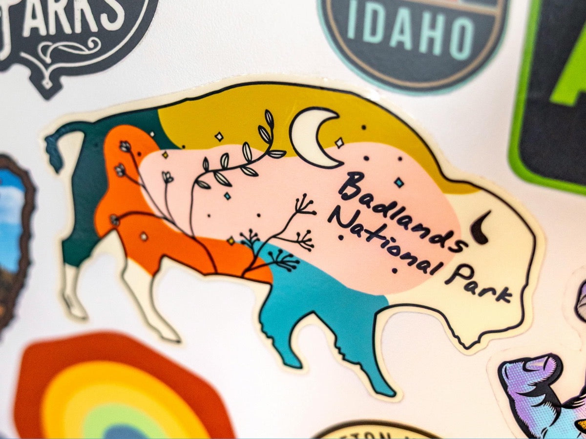A bison-shaped die-cut sticker among other vinyl stickers on a laptop.